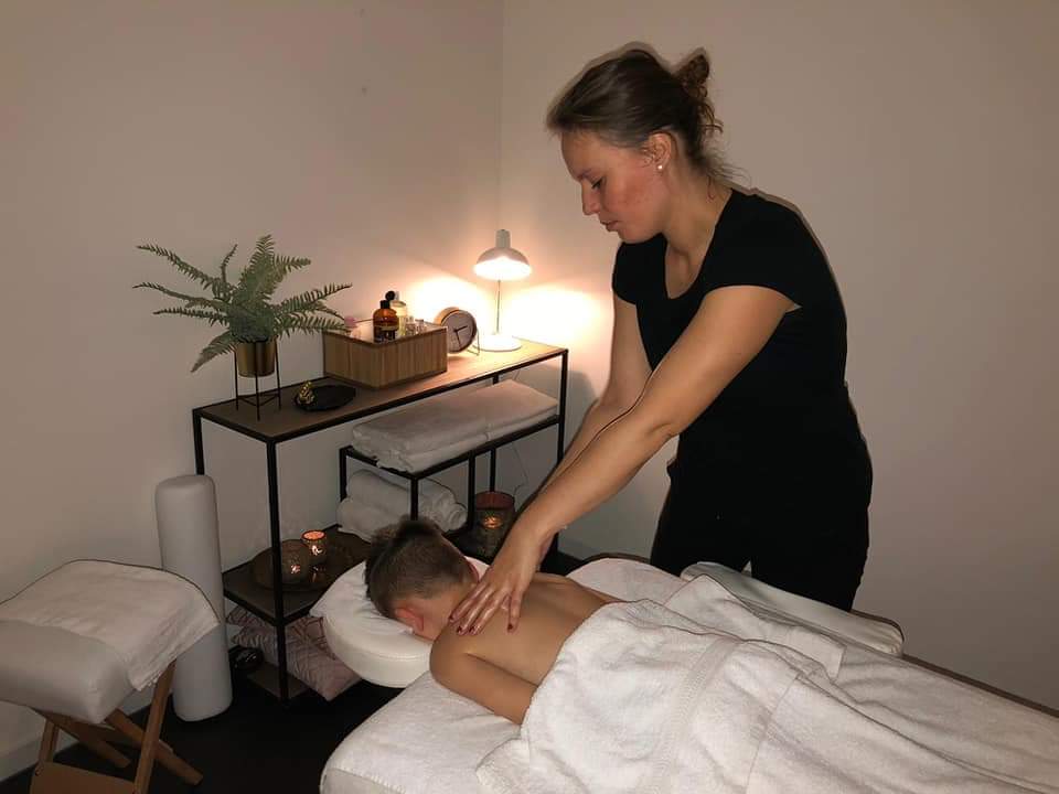 Talitha geeft een rugmassage in de behandelruimte, in warm lamplicht